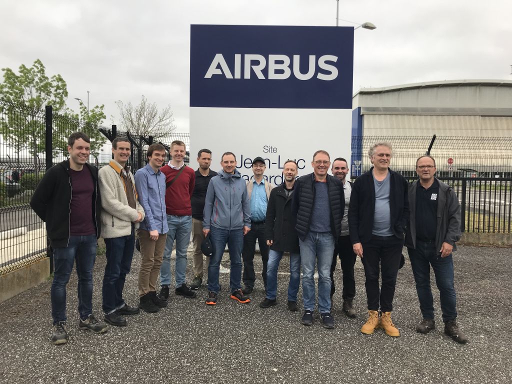 12 Personen vor dem AIRBUS Firmenschild