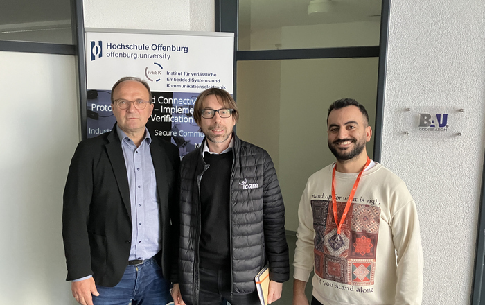 3 Personen nebeneinandervor dem RollUp des Institues