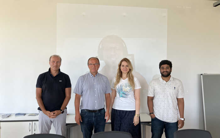 4 Personen vor einer Leinwand auf der der 5. Teilnehmer zu sehen ist