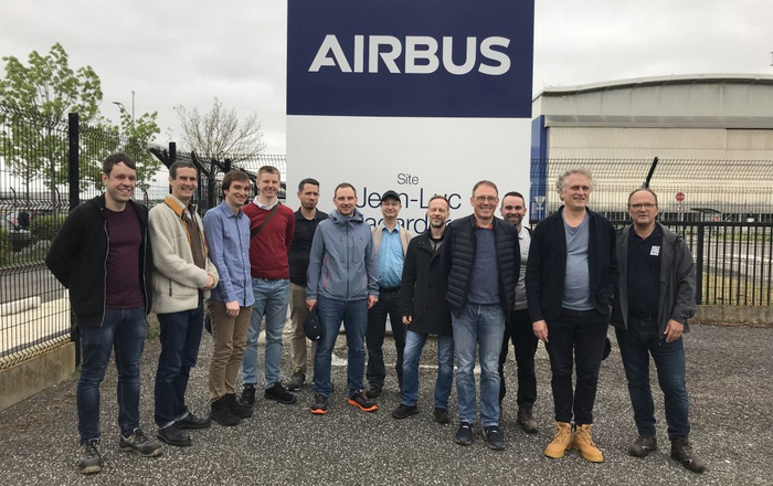 12 Personen vor dem AIRBUS Firmenschild